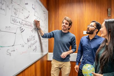 Research Fellow Maggie Lieu, Post doc Swagat Mishra with Post graduate Sergio Sevillano at a white board, discussing the expansion of the Universe, and the evidence for the Big Bang i.e. the Cosmic Microwave Background (the inflatable ball) in Cripps North Building