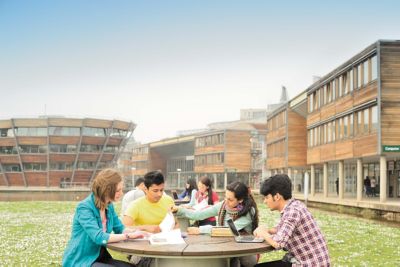 Students studying on the grassy area outside the Djanolgly Learning Centre on Jubilee Campus