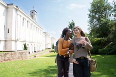 Two undergraduate students laughing outside of the Trent building