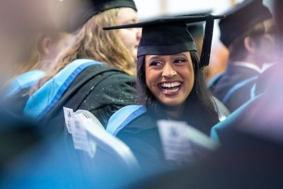 A close-up of a smiling student at May graduation 2022