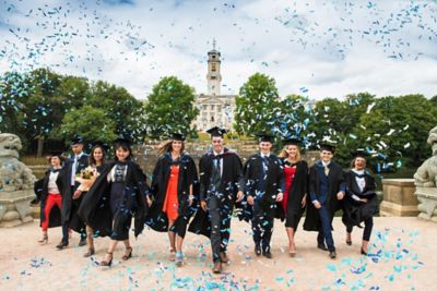Group of graduates walking through blue confetti in front of Trent Building on Highfields Park at the Summer graduation ceremony July 2018 by Simon LitherlandCopyright belongs to University of Nottingham. Photography by Simon Litherland.