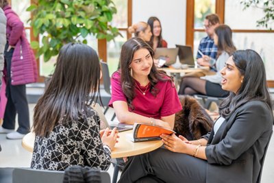 Students discussing a text book in a group study session in the atrium of the Law and Social Sciences