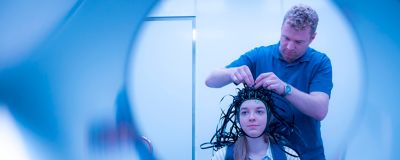 Being attached by Professor matthew Brookes, female PhD student Molly Rea wearing a MEG system that can be worn like a helmet, allowing free and natural movement during scanning October 2019. Photography by Lisa Gilligan-Lee.Copyright belongs to the University of Nottingham.https://www.nottingham.ac.uk/research/beacons-of-excellence/precision-imaging/our-projects/meg/meg.aspx