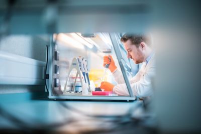 Postgraduate student filling test tubes in a fume hood in the Tissue Culture Laboratory, Nottingham Medical School, Queens Medical Centre