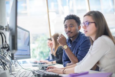 Two undergraduate students in the robotics lab, looking at a desktop computer screen