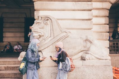 Undergraduate students standing in front of the Nottingham Council House lions in Nottingham City Centre - November 2021.Izzy Armorgie (blue hair) and Mariam Abedraba Abdalla (pink hat)