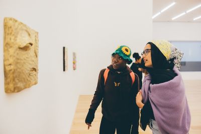 Undergraduate students looking at art work in the Nottingham Contemporary, Nottingham City Centre - November 2021. Mariam Abedraba Abdalla (pink hat) and Bolusefe Akande (sunflower hat).