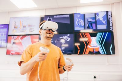 Undergradute student using a virtual reality headset in the Product Design Studio infront of screens