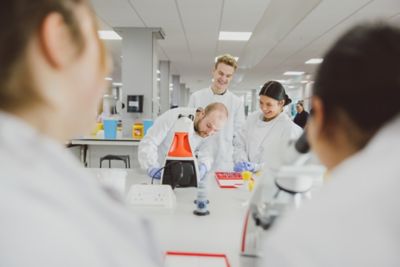 Group of undergraduate students standing around a microscope in the STEM lab on Sutton Bonington Campus