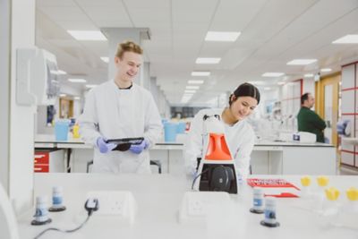 Two undergraduate students behind a desk with a microscope on it in the STEM lab on Sutton Bonington Campus
