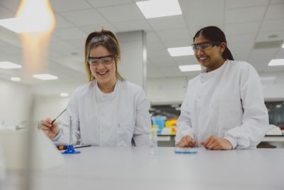 Two undergraduate students wearing PPE using a Bunsen burner in the STEM lab on Sutton Bonington Campus