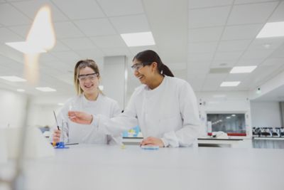 Two undergraduate students wearing PPE using a Bunsen burner in the STEM lab on Sutton Bonington Campus