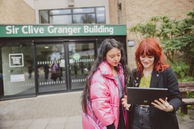 Pair of undergraduate students looking at laptop outside Clive Granger building, University Park campus