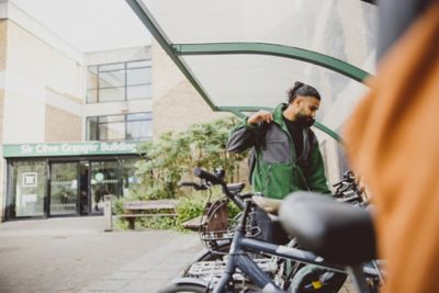 An undergraduate student using a bike shelter outside the Clive Granger building, University Park campus