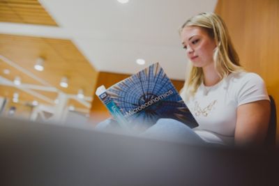 Undergraduate student reading an economics textbook, Monica Partridge building