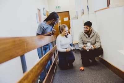 Undergraduate students playing with a smart robot outside the Law Tech lab, Law and Social Sciences Building