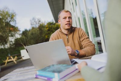 Undergraduate student using a laptop outside the Monica Partridge building, University Park campus