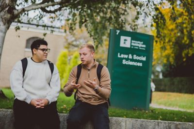 Undergraduate students sitting outside the Law and Social Sciences building, University Park campus