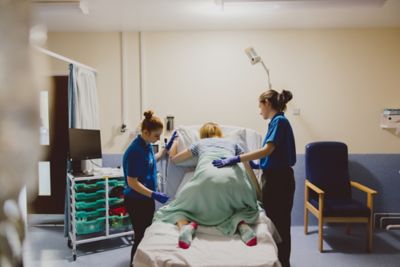 Undergraduate students practicing delivering a newborn baby with a SimMom in the Health Sciences QMC Clinical Skills suite