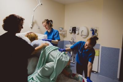 Undergraduate students practicing delivering a newborn baby with a SimMom in the Health Sciences QMC Clinical Skills suite