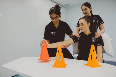 Undergraduate students practising a cone stacking exercise with a Teaching Associate