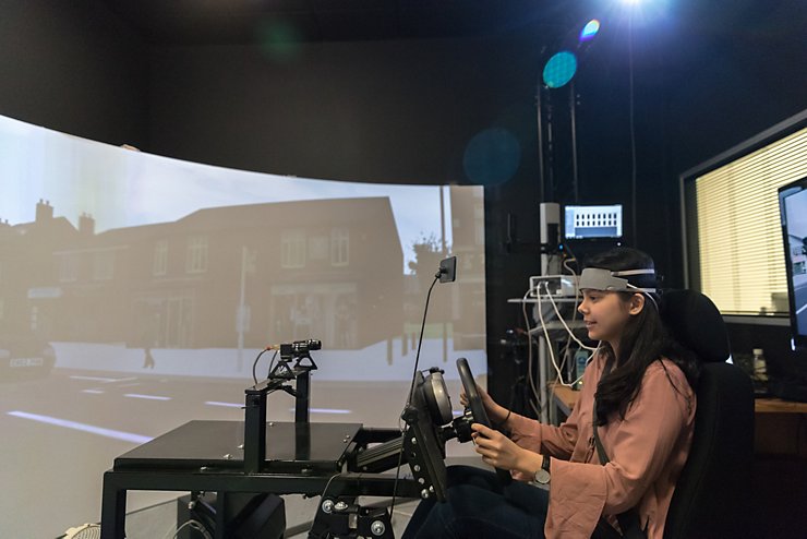 Undergraduate student sat in driving simulator wearing headset and using handheld controls to conduct experiment