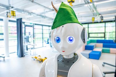 White human-style robot, Robin, with blue eyes wearing a Robin Hood hat in Robot lab