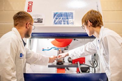 Undergraduate students placing a pre-prepared aluminum billet into the Computer Numerical Controlled (CNC) milling machine