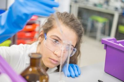 Undergraduate chemistry practical chemistry student working in a lab, wearing safety goggles